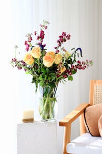 A graceful bouquet of roses and wildflowers in a vase, brightening a sunny room.