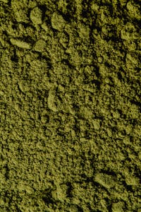 Closeup view of coarse green matcha powder texture, ideal for backgrounds and culinary themes.